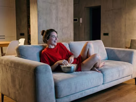 Девушка смотрит телевизор лёжа на диване