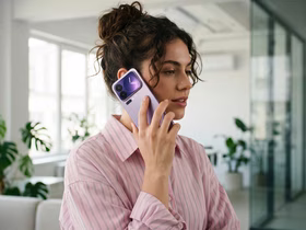 Девушка в розовой полосатой рубашке держит у уха Xiaomi 18 Pro