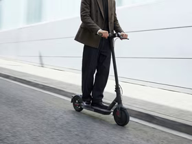 Мужчина в костюме едет на самокате