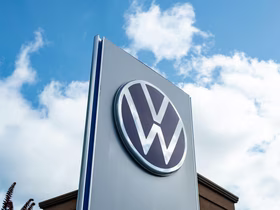 Логотип Volkswagen на стеле рядом с коричневым зданием