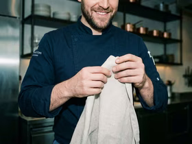 Мужчина в форме повара держит в руках полотенце