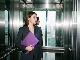 Девушка в лифте с фиолетовой папкой в руках