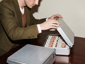 Мужчина открывает коробку, в которой лежат пачки пятитысячных российских купюр