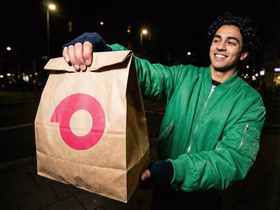 Мужчина держит в руках пакет с логотипом сервиса доставки Самокат