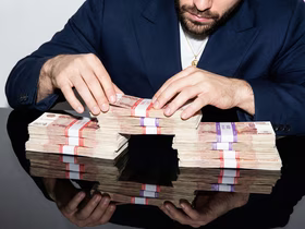 Мужчина трогает пачку денег, состояющую из пятитысячных купюр