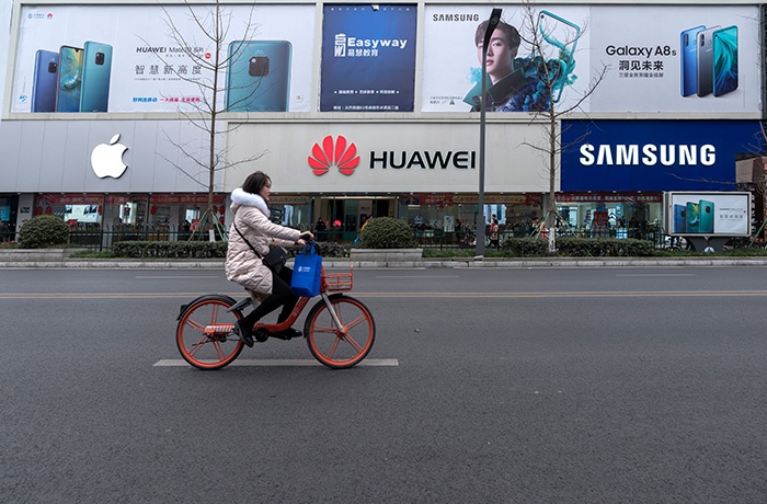 Девушка проезжает на велосипеде мимо магазинов смартфонов